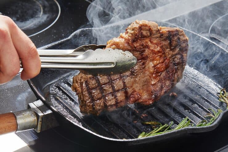 Steak cooking on a grill pan with visible sear marks